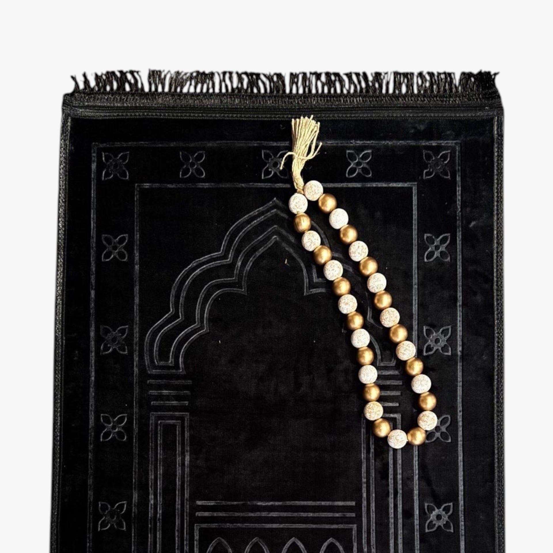 Black prayer mat with a string of prayer beads on a white background