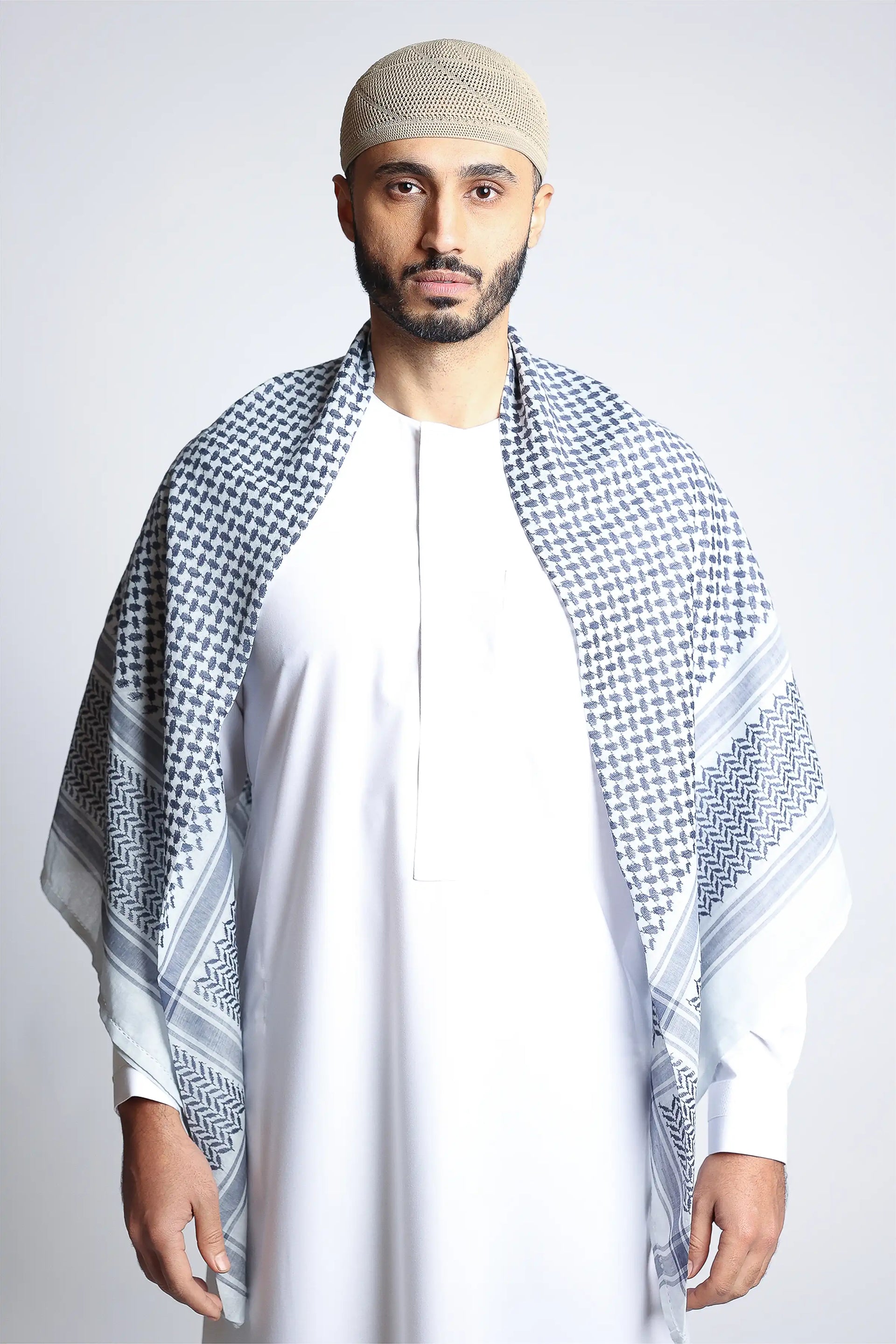 A man wearing a white bisht and a gunpowder blue shemagh headscarf.