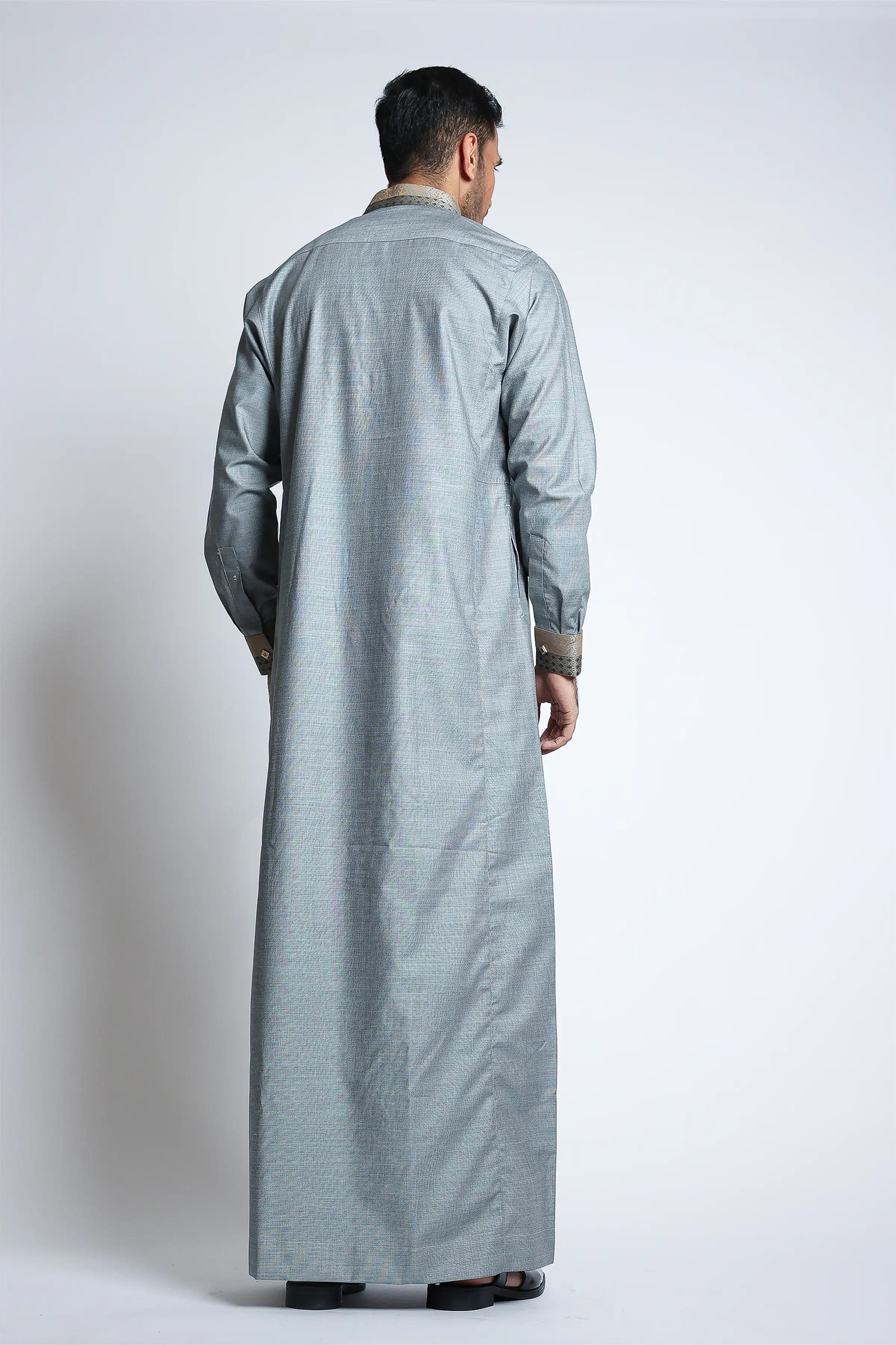 Man wearing a long light gray dress on a white background